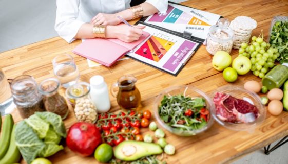 Writing a diet plan on the table full of healthy food